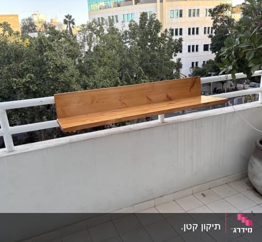 ספסל עץ מותקן על מעקה מרפסת.
